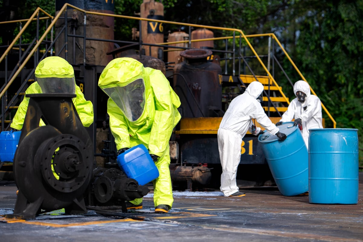 Hazmat workers in protective suits handling hazardous materials